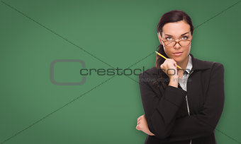 Serious Young Woman with Pencil In Front of Blank Chalk Board