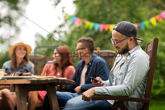man with smartphone and friends at summer party