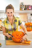 housewife carving a big orange pumpkin Jack-O-Lantern in kitchen