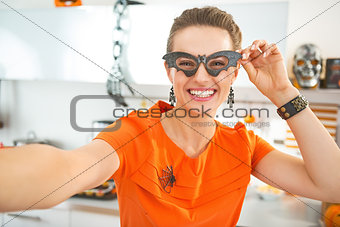 smiling woman in Halloween decorated kitchen taking selfie
