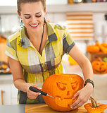 happy housewife carving a big orange pumpkin Jack-O-Lantern