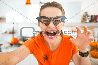 happy young woman in Halloween decorated kitchen taking selfie