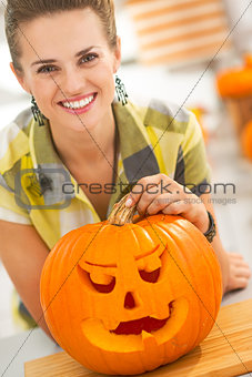 woman with a big orange pumpkin Jack-O-Lantern in kitchen