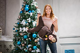 Young woman playing with little son dressed in monkey costume beside Christmas tree