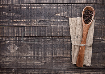 Pepper on spoon and kitchen towel on wooden board