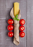 Raw spaghetti in linen cloth with tomatoes and basil