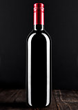 Bottle of red wine dark glass on wooden bacground