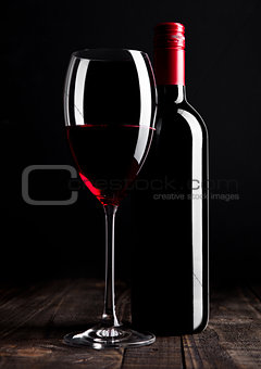 Red wine bottle and glass on wooden table black