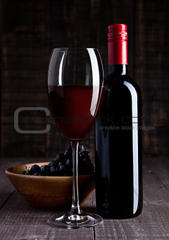 Bottle and glass of red wine with grapes in bowl