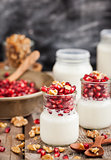 Fresh yogurt with pomegranate seeds and walnut in a glass jars