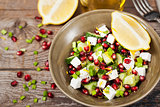 Fresh  green salad with pomegranate seeds, cucumber and feta che