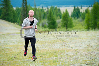 Man running on grass field at mountain background