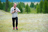 Man uses a smart watch during the run in the mountains.