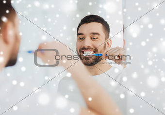 man with toothbrush cleaning teeth at bathroom
