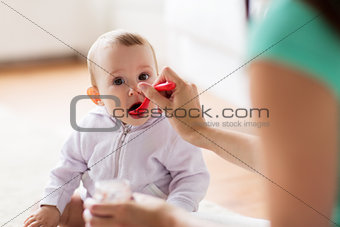 mother with spoon feeding little baby at home