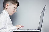School child looking at computer over gray background