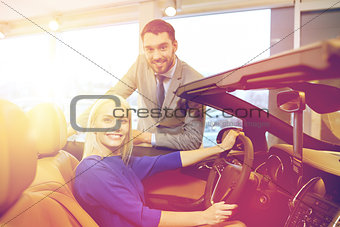 happy couple buying car in auto show or salon