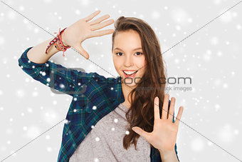 smiling teenage girl showing hands over snow