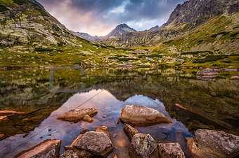 Mountain Lake with Rocks in Foreground at Sunset 