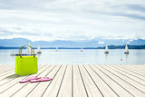 green bag on a wooden jetty with sailing boats in the background