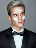 Beautiful face of imposing man with cosmetic cream on cheeks, spa treatment