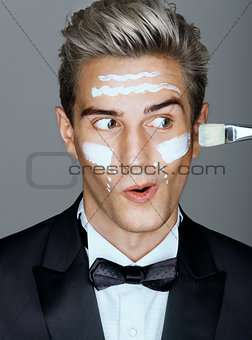 Funny classy man with cream lines on face, spa treatment.