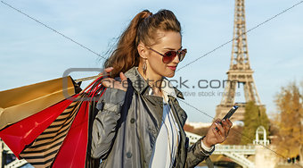 trendy woman with shopping bags writing sms near Eiffel tower