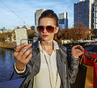 trendy woman with shopping bags taking selfie with phone, Paris