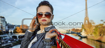 trendy woman with shopping bags in Paris using smartphone