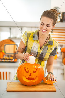 housewife putting candle inside orange pumpkin Jack-O-Lantern