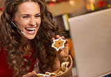 Smiling young woman showing christmas cookies while having video
