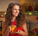 Happy young woman with cup of ginger tea looking on copy space