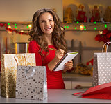 Happy young woman checking list of christmas presents