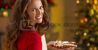 Portrait of smiling young housewife with plate of christmas cook