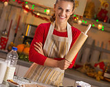 Portrait of smiling young housewife with rolling pin