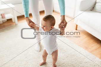 happy baby learning to walk with mother help