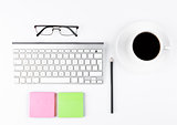 White keyboard with glasses and sticky note papers