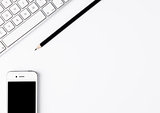 White keyboard with black pencil and phone on desk