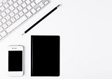 White keyboard with black pencil and phone on desk
