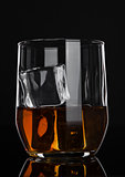 Glass of whiskey with ice on wooden background
