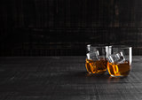 Glasses of whiskey with ice on wooden background