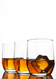 Glasses of whiskey with ice cubes and reflection