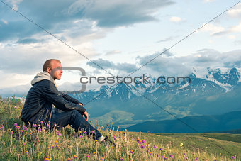Traveler sitting on top of a mountain and looks into the distance. Mountains.