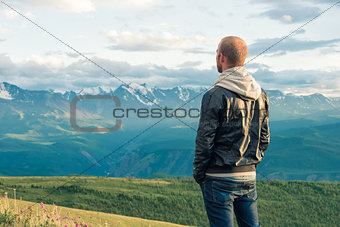 Traveler stay on top of a mountain and looks into the distance. Mountains.
