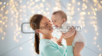 happy young mother with little baby over lights