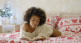 Calm beautiful African woman reading in bed