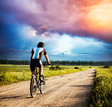 Man Riding a Bike on Country Road at Sunset