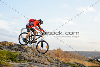 Cyclist in Red Jacket Riding the Bike Down Rocky Hill. Extreme Sport.
