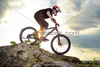 Professional Cyclist Riding the Bike Down Rocky Hill at Sunset. Extreme Sport.