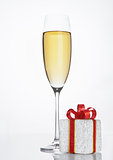 Glass of sparkling champagne with red gift box